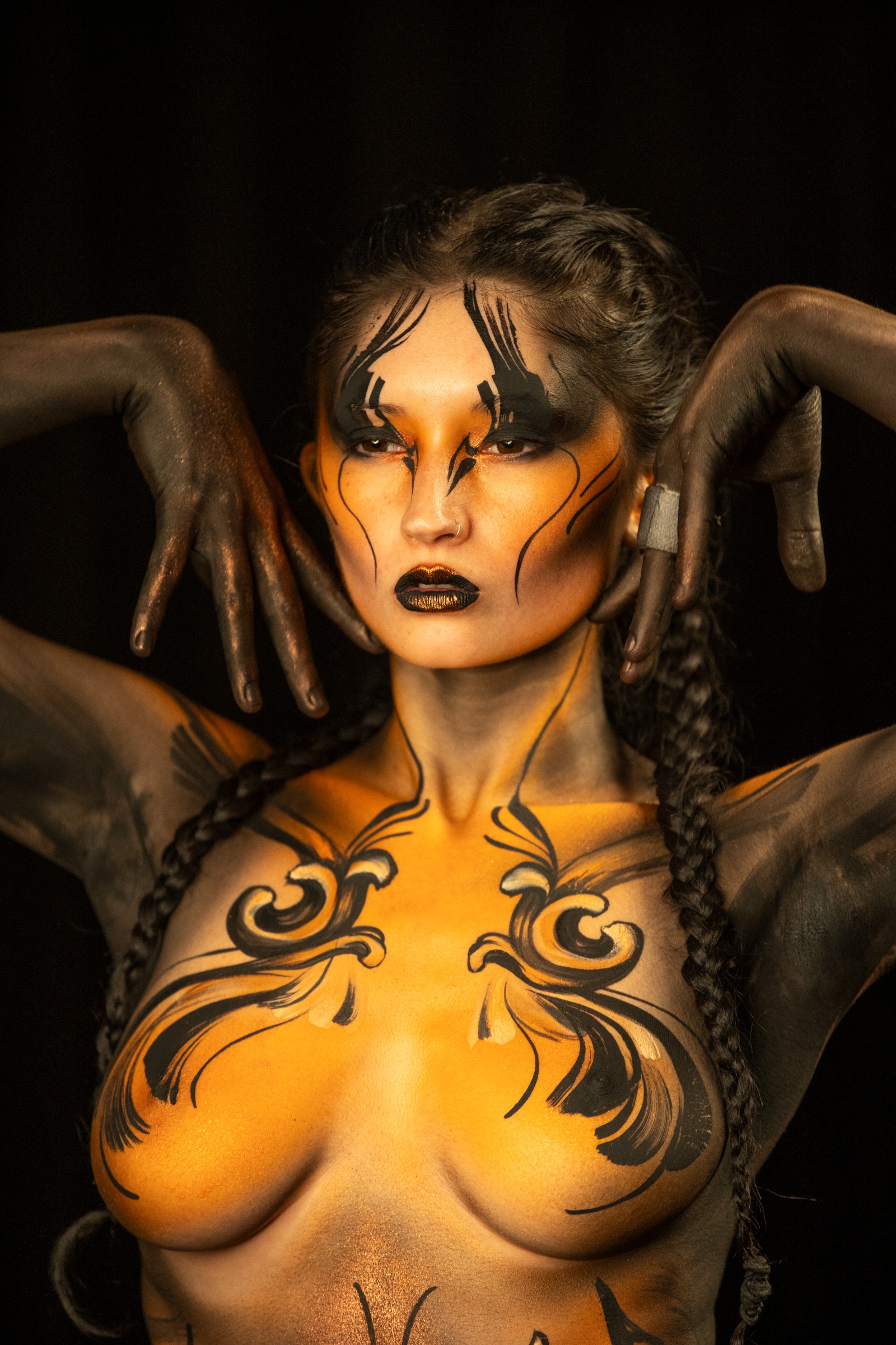 BabeyGianna stands facing forward, looking upward toward the camera. Her torso carries an orange and black floral scrollwork pattern, photographed under UV light. Bodypaint by Claudia Kraemer. Photographed by Elad Itzkin Photography in his studio in Gesundbrunnen, Berlin.