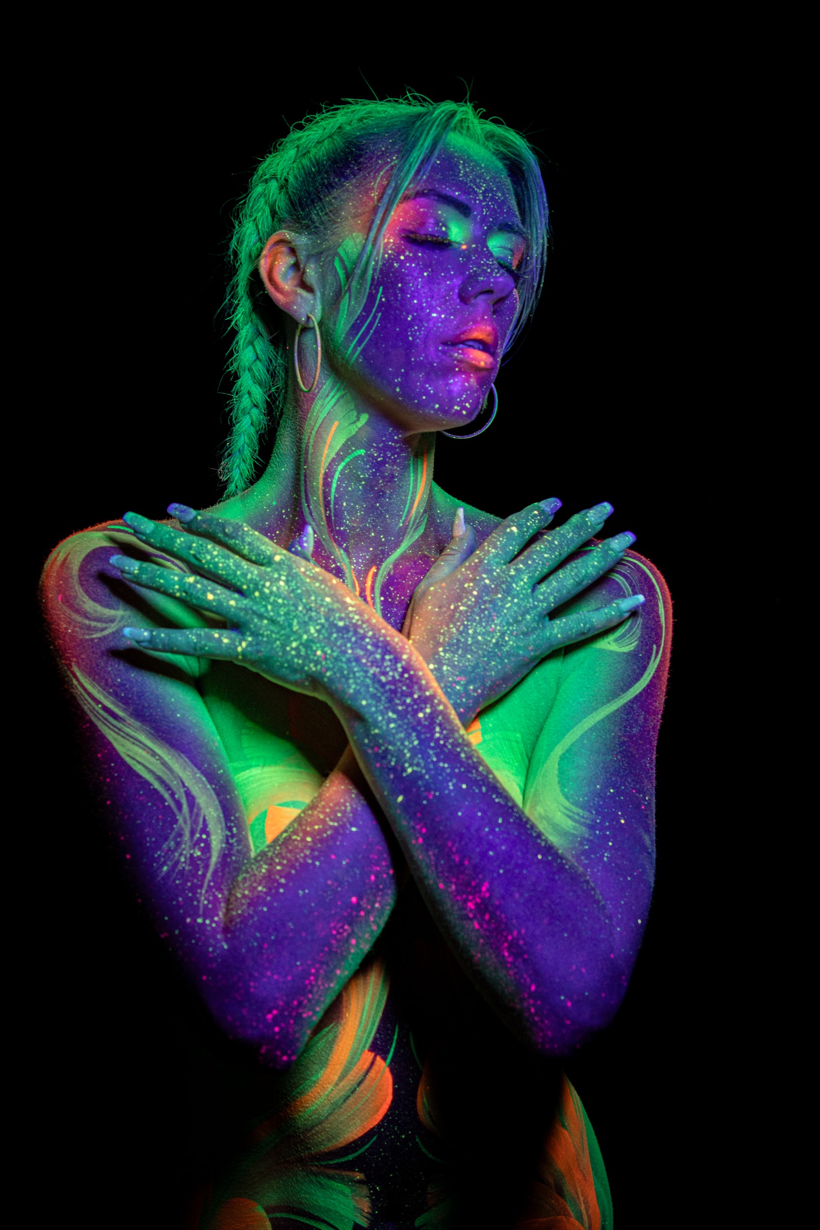 Miss_Layla_X stands facing forward, her torso painted with a symmetrical floral pattern in glowing green, orange, and purple. Bodypaint by Claudia Kraemer. Photographed by Elad Itzkin Photography under UV blacklight in his studio in Gesundbrunnen, Berlin.